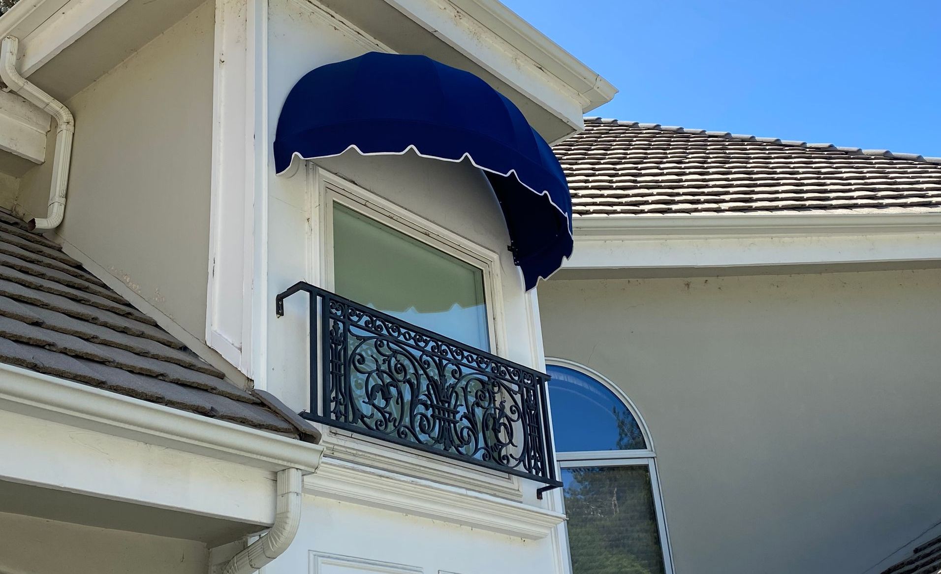 A white house with a blue awning over a window
