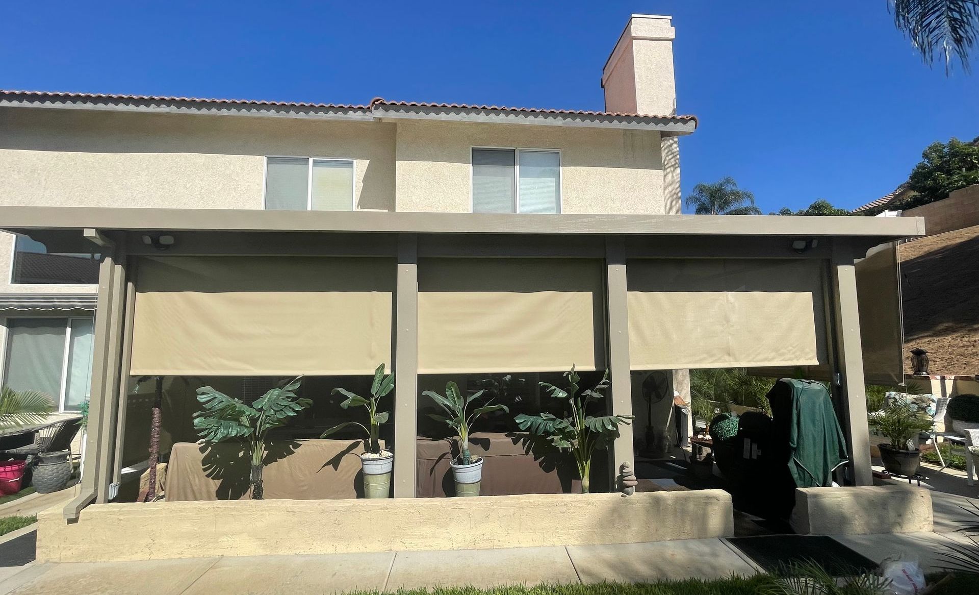 A house with a covered porch with shades on it.