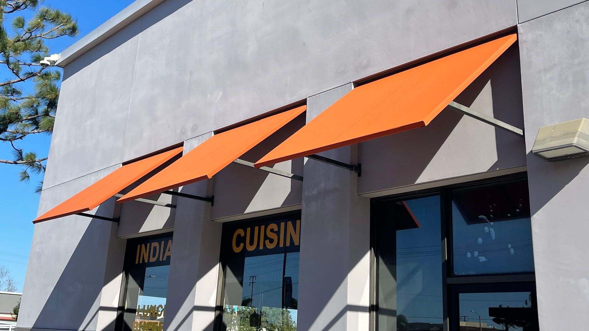 A building with a sign that says cuisine on it and orange awnings