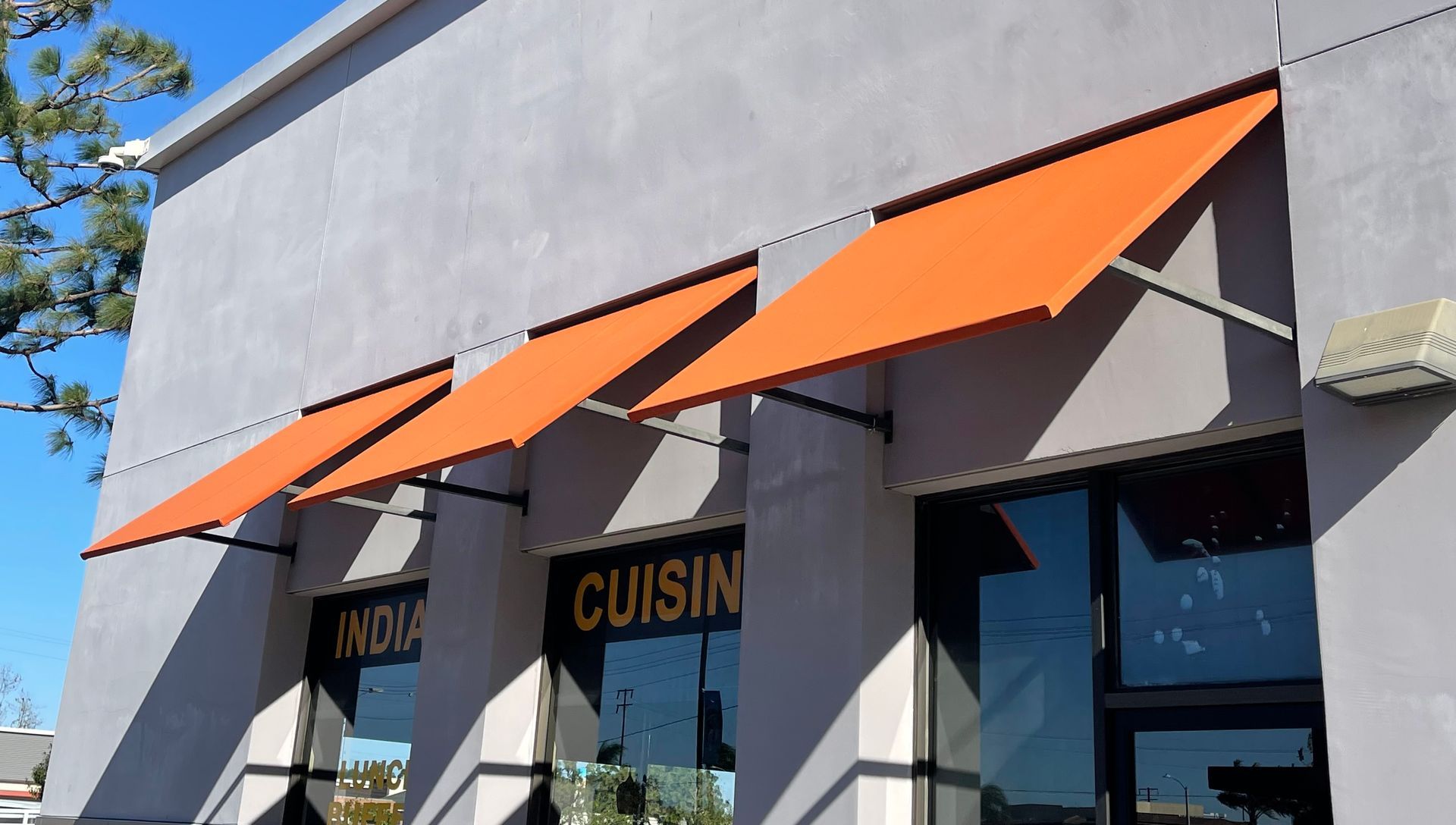 A building with a sign that says cuisine on it and orange awnings