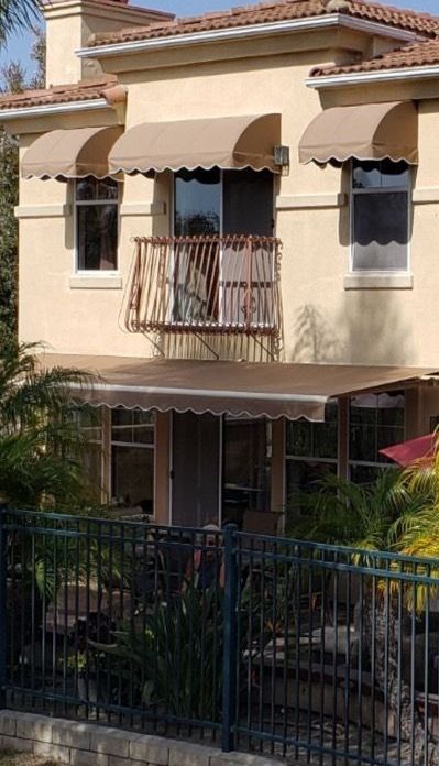 A house with a balcony and awnings on the windows.