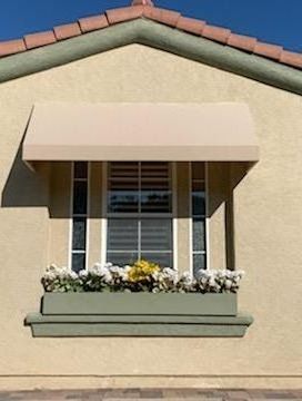 A window with flowers in a window box on the side of a house.