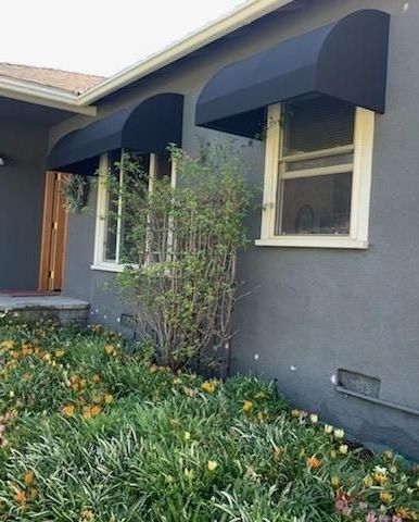 A gray house with a black awning on the windows.