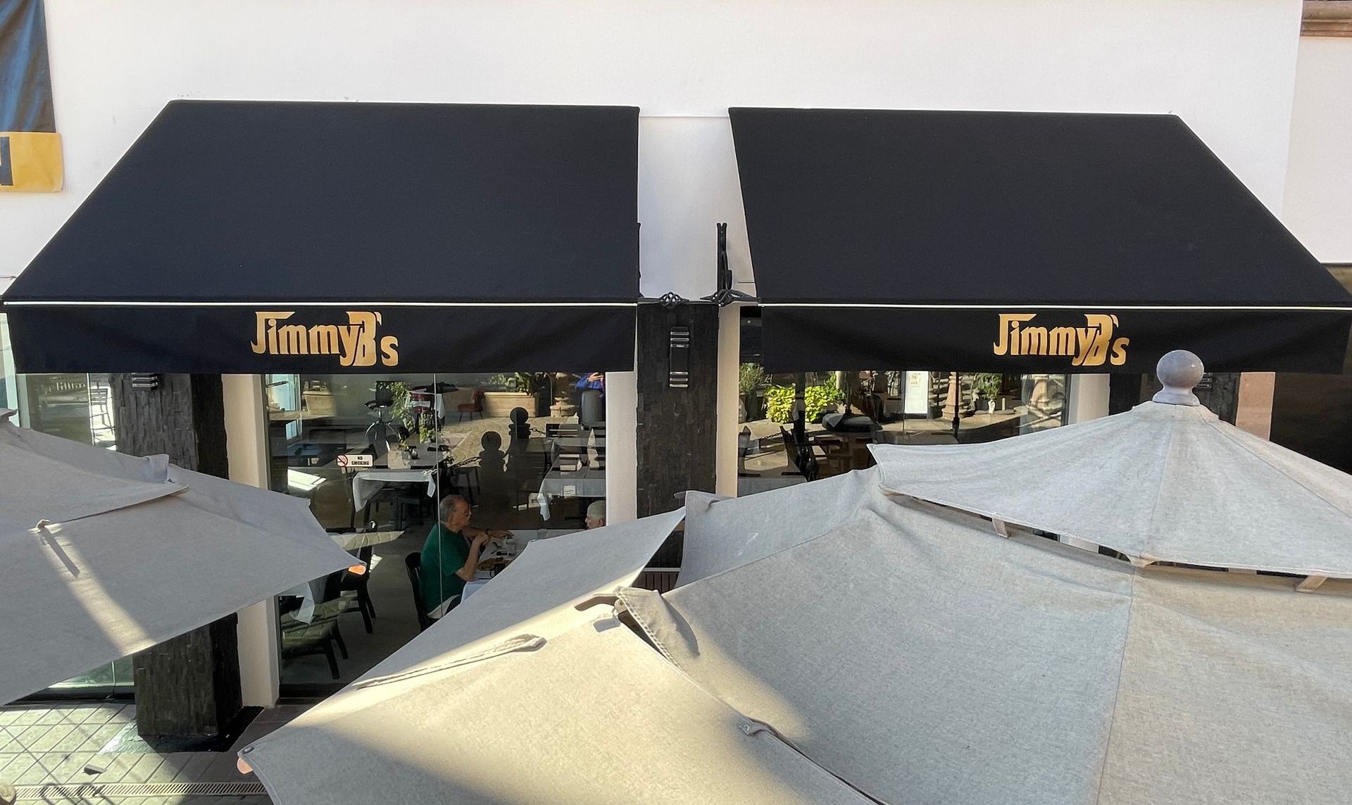 A restaurant with a black awning that says jimmy 's