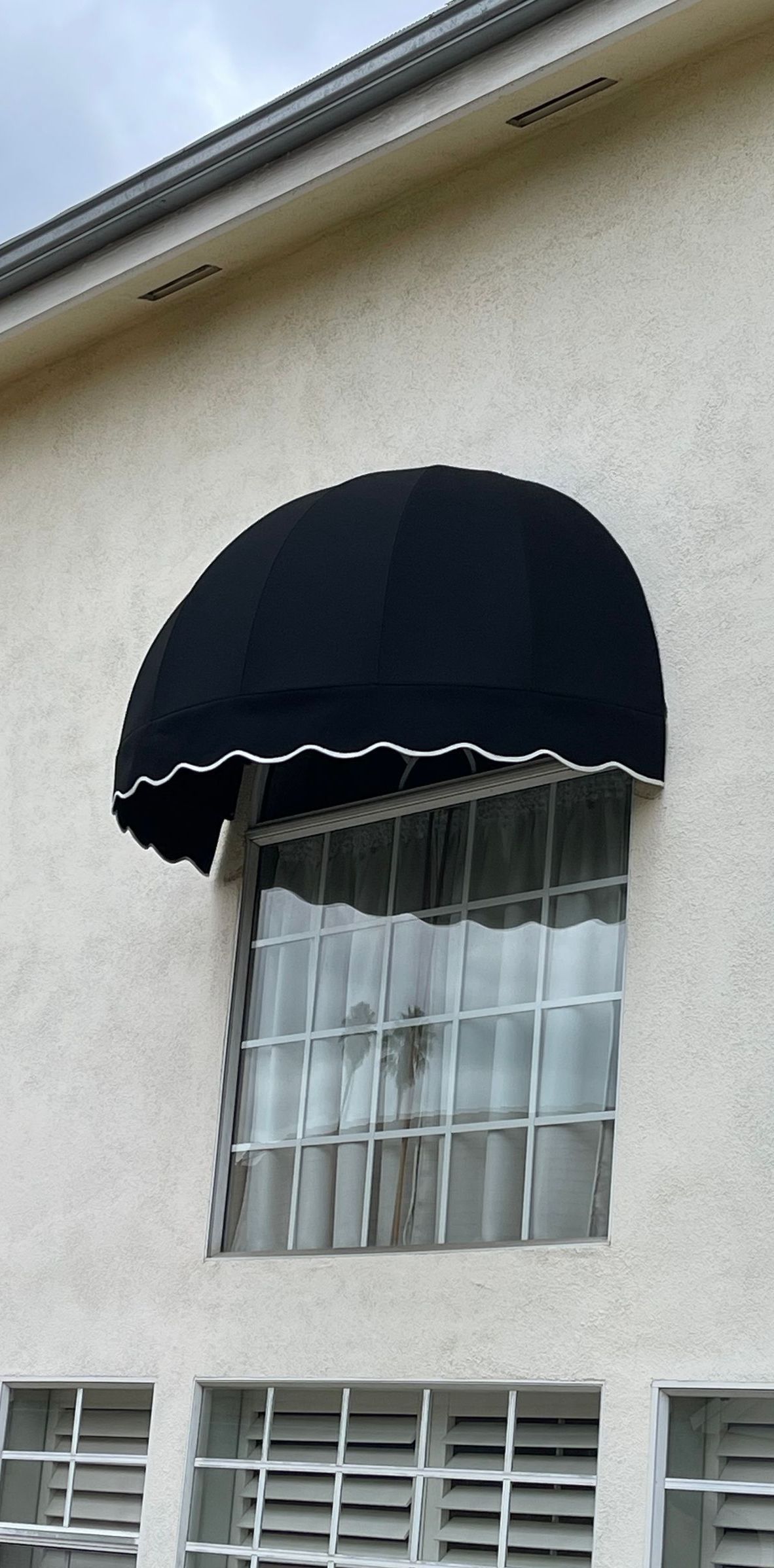 A white building with a black awning over a window.