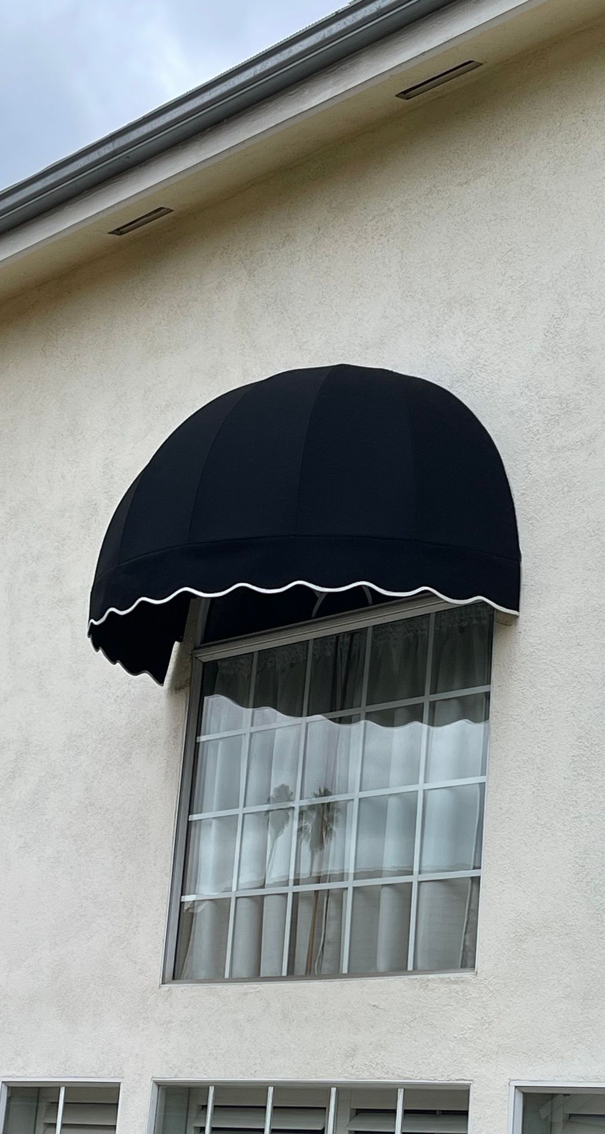 A white building with a black awning over a window.