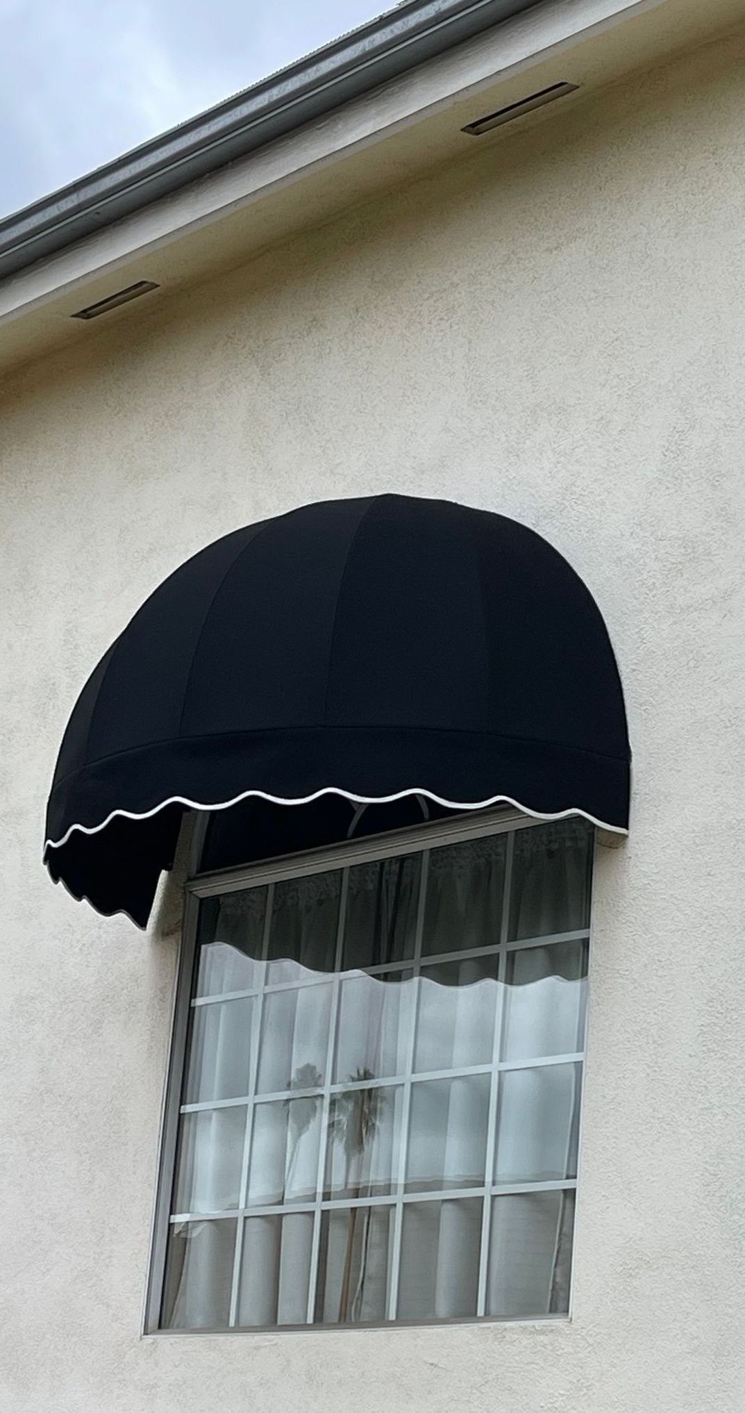 A white building with a black awning over a window.
