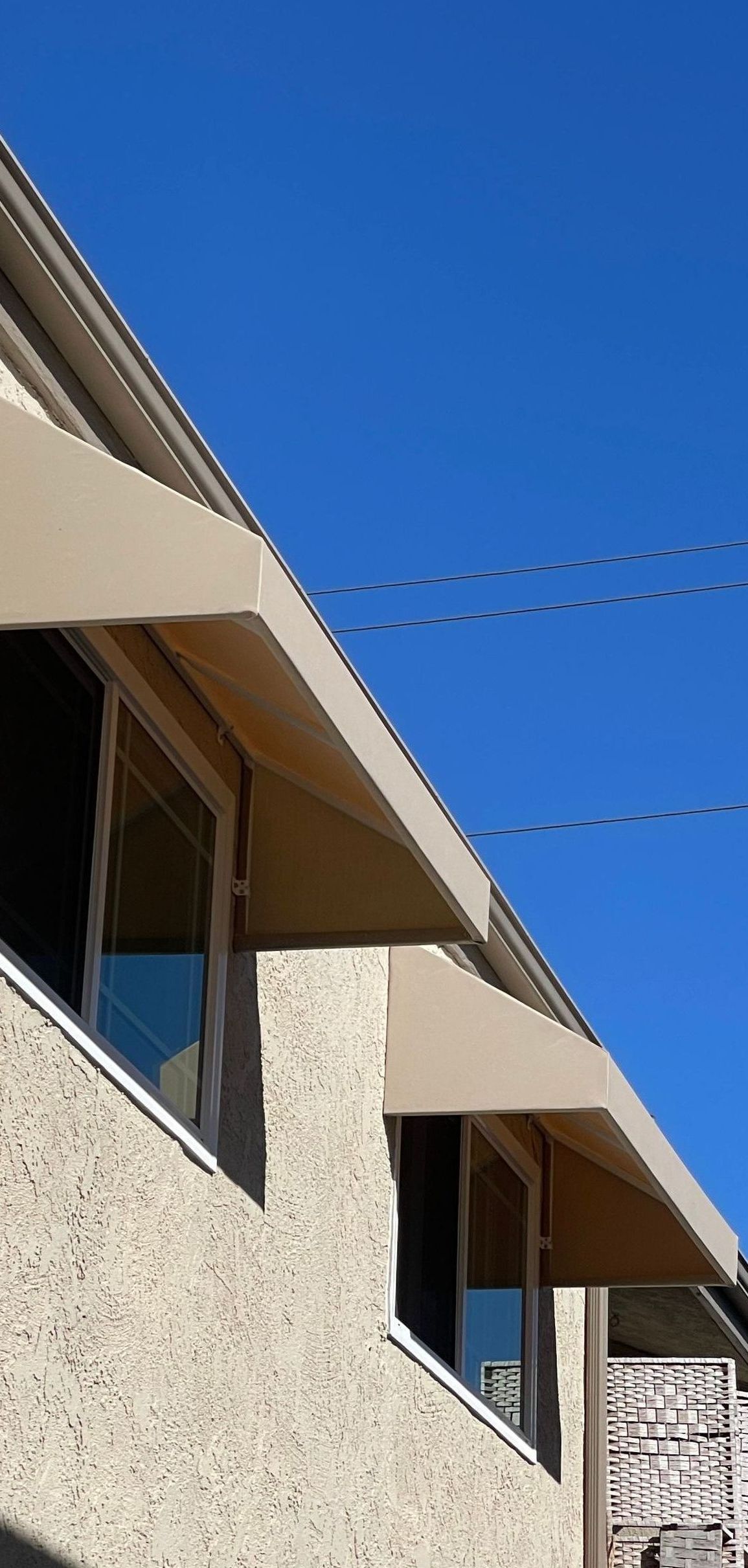 A building with a canopy on the side of it and a blue sky in the background.