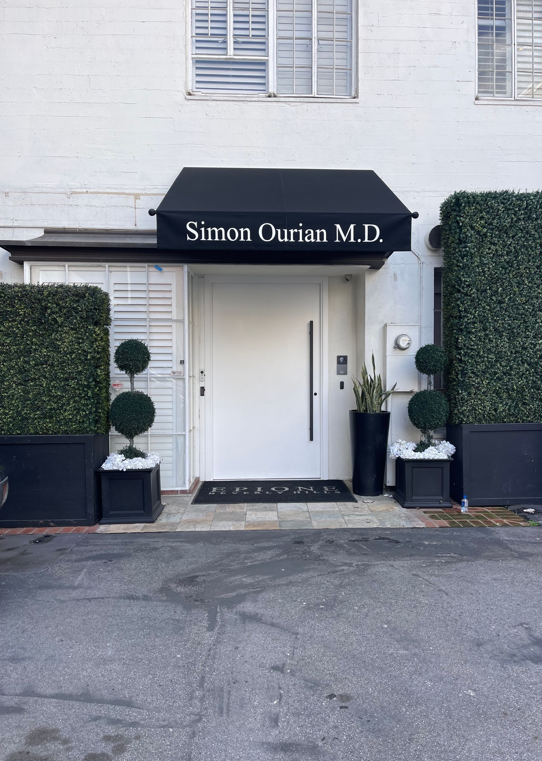 A white building with a black awning over the front door.