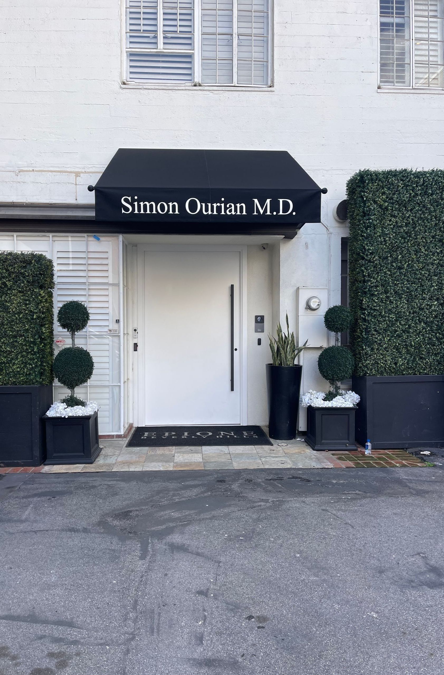 A white building with a black awning over the front door.