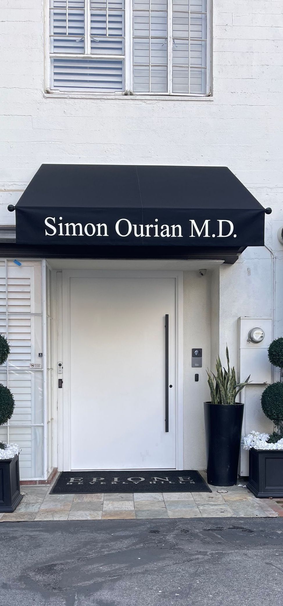 The front door of a building with a black awning over it.