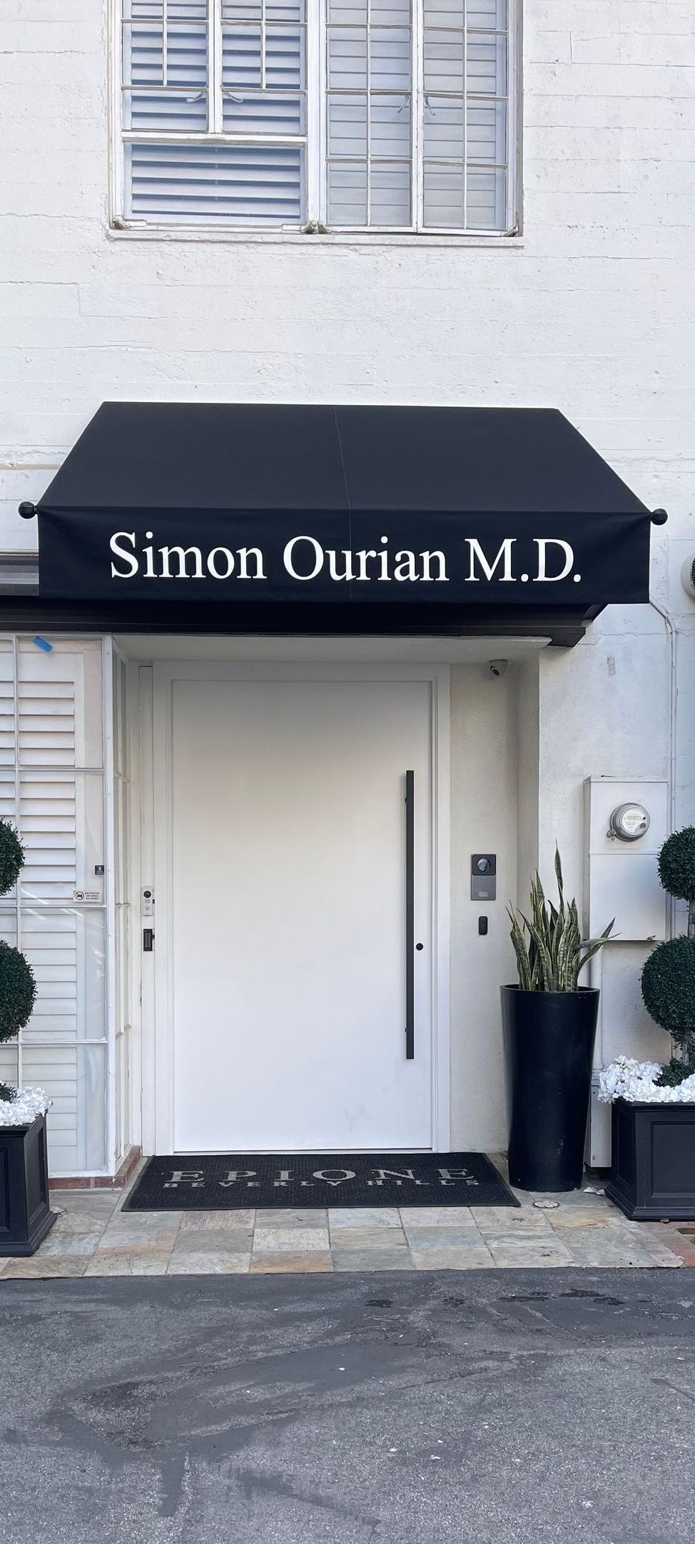 The front door of a building with a black awning over it.