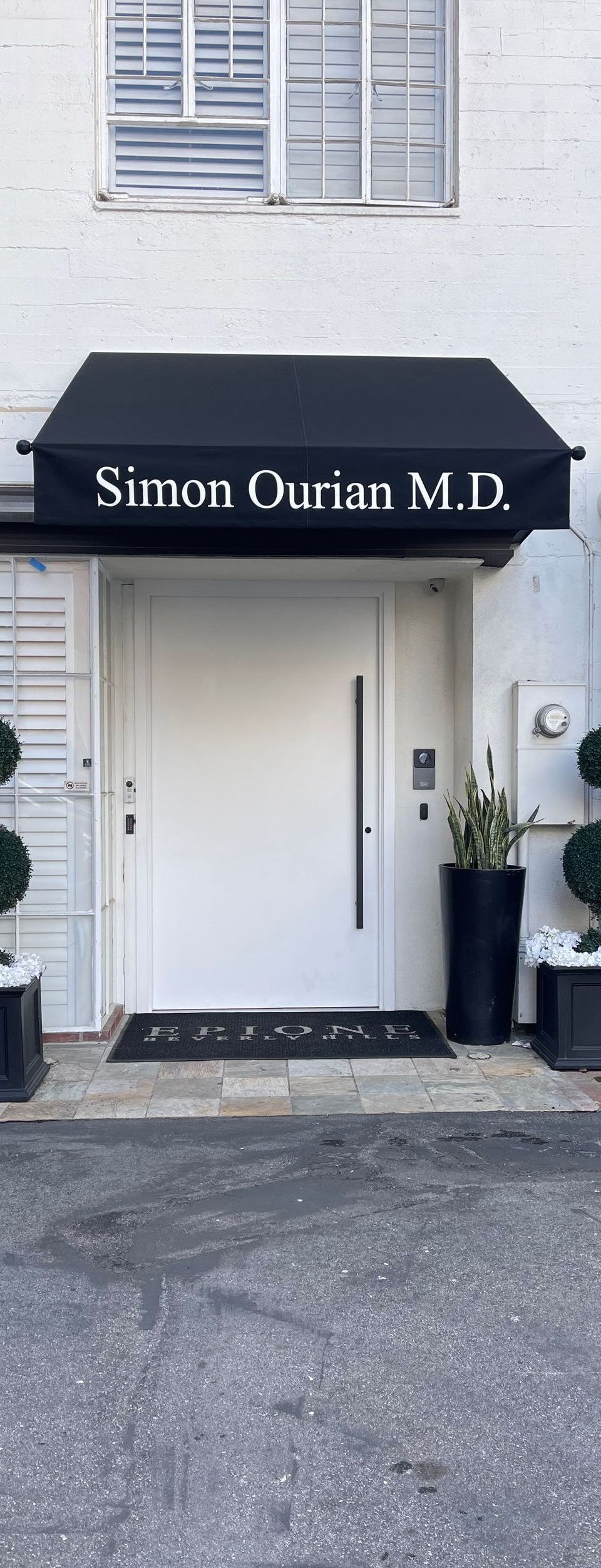 Exterior of a white medical office with a black awning that reads 