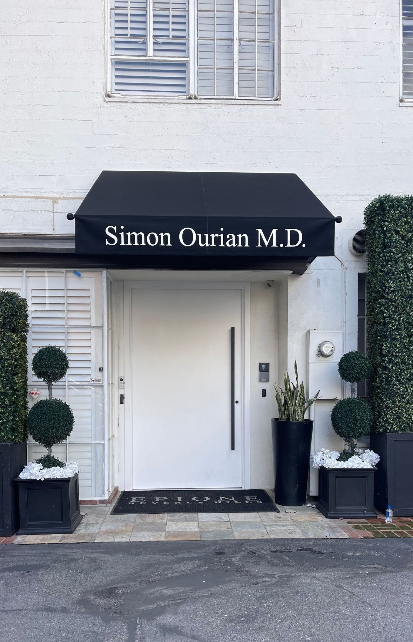 A white building with a black awning that says sirrain durian m.d.