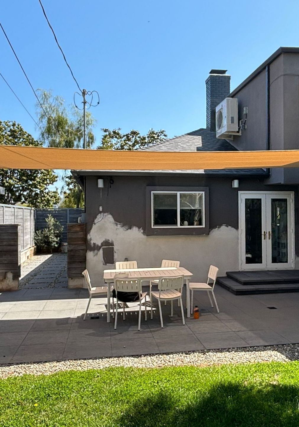 A person is laying on a lounge chair under an awning on a patio.