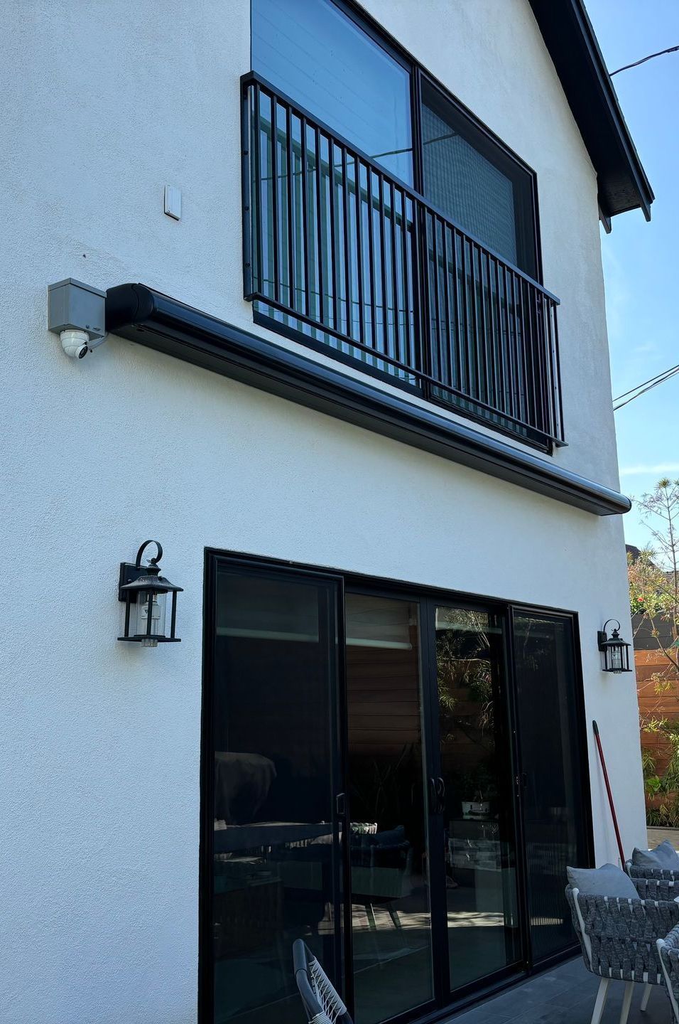 A white house with a balcony and sliding glass doors.