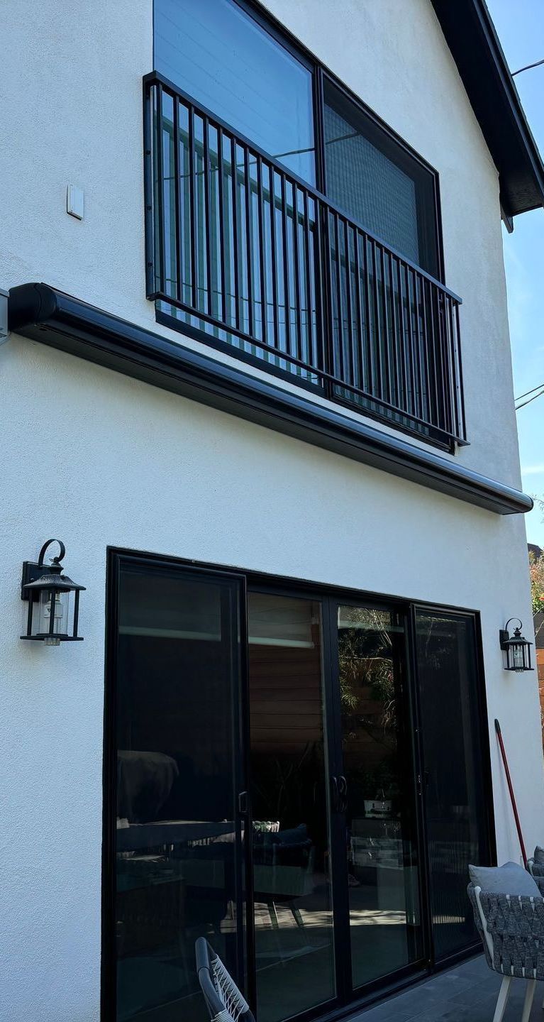 A white house with a balcony and sliding glass doors.