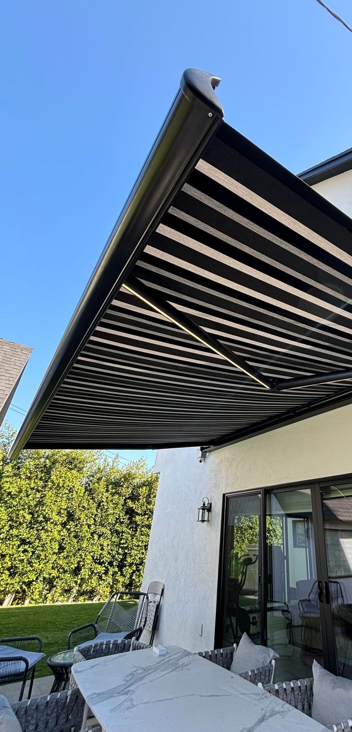 A black awning is covering a patio with a table and chairs.