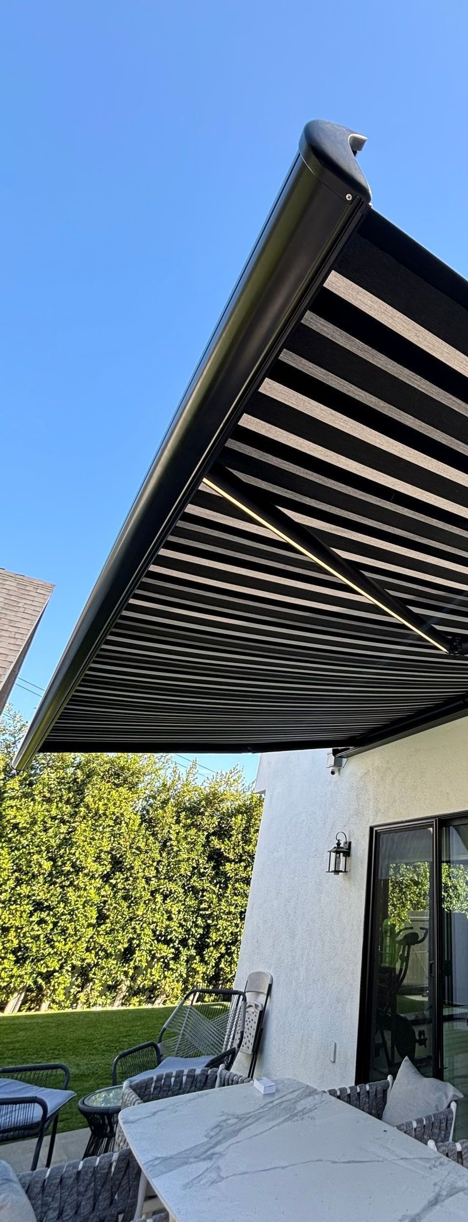 A black awning is covering a patio with a table and chairs.