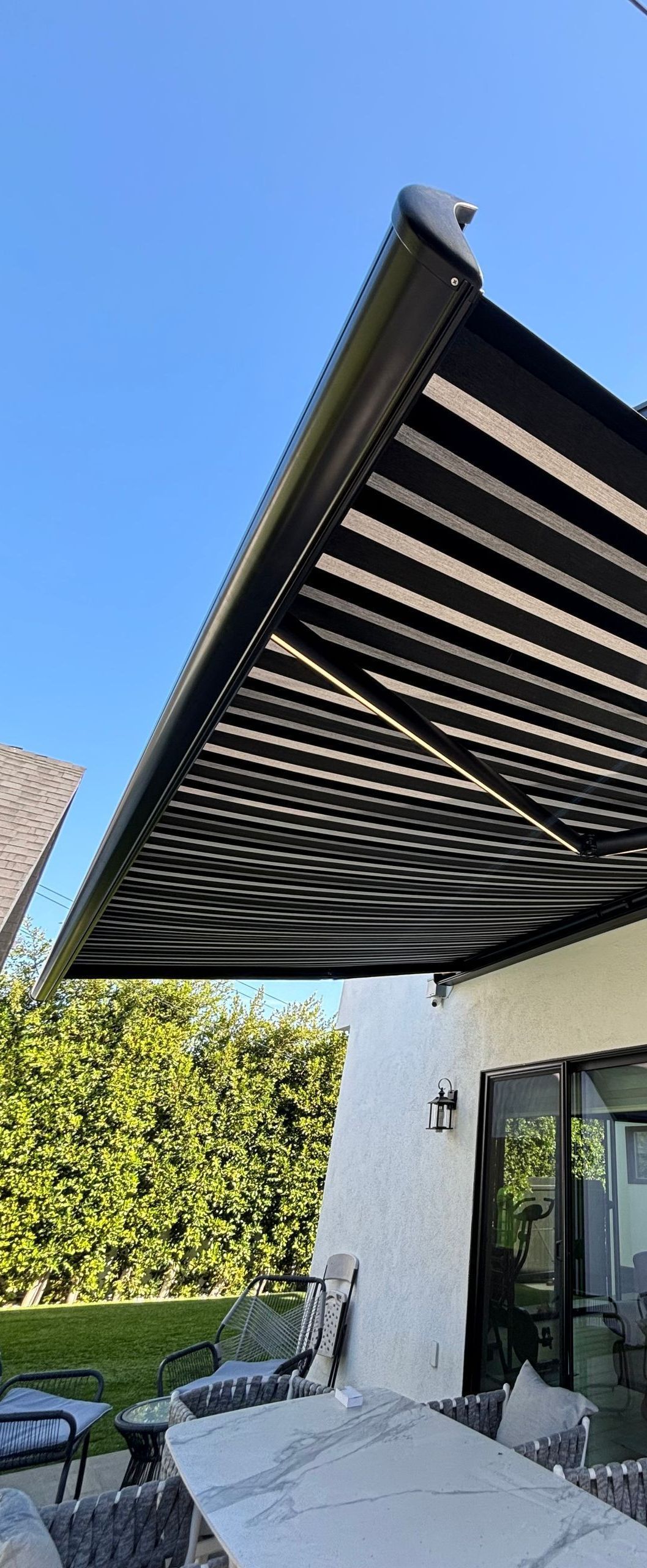 A black and white awning is covering a patio with a table and chairs.