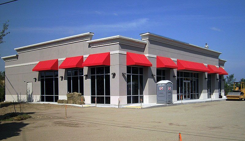 A gray building with red awnings on the windows