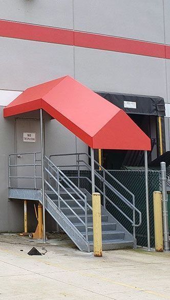 A red awning over a set of stairs in front of a building