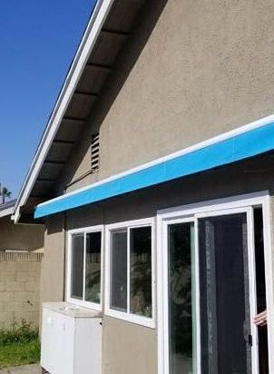 A house with a blue awning and a sliding glass door.