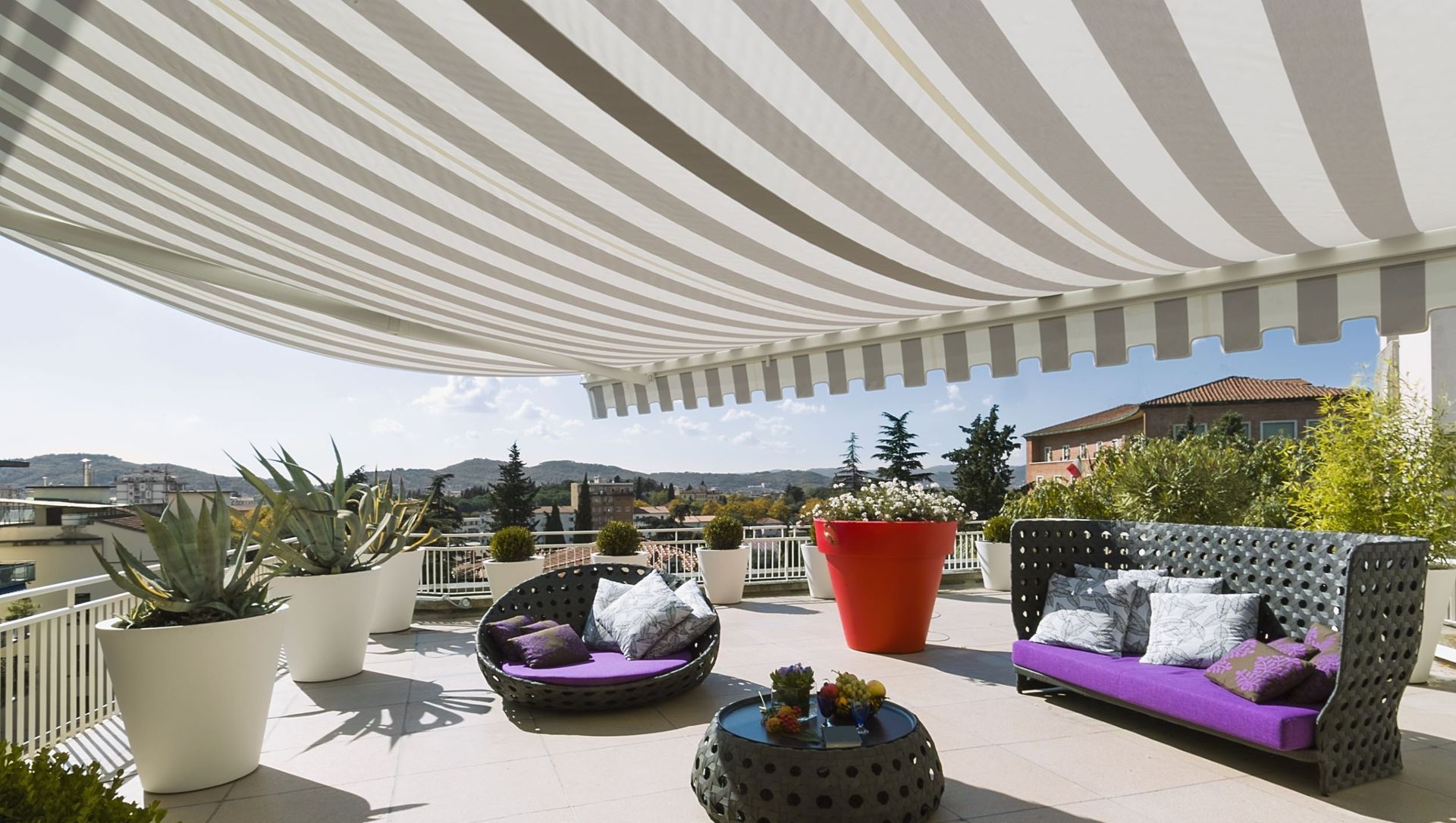 A patio with a striped awning and purple furniture