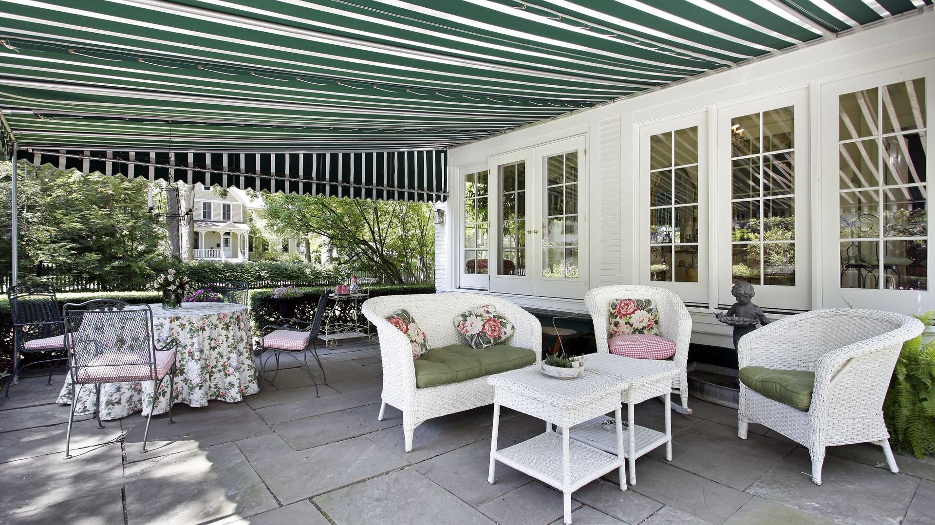 A patio with white furniture and a green and white striped awning