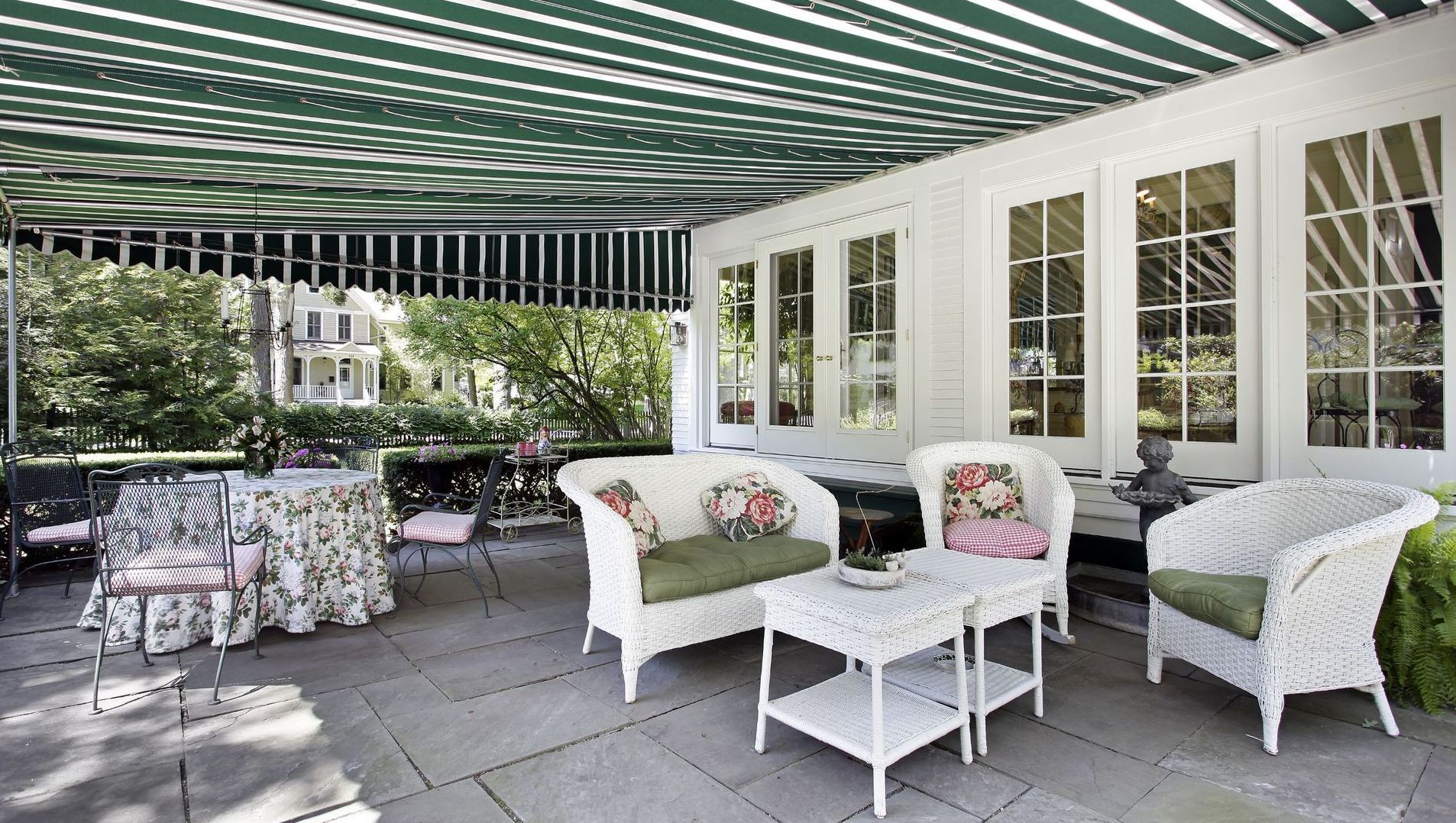 A patio with white furniture and a green and white awning.