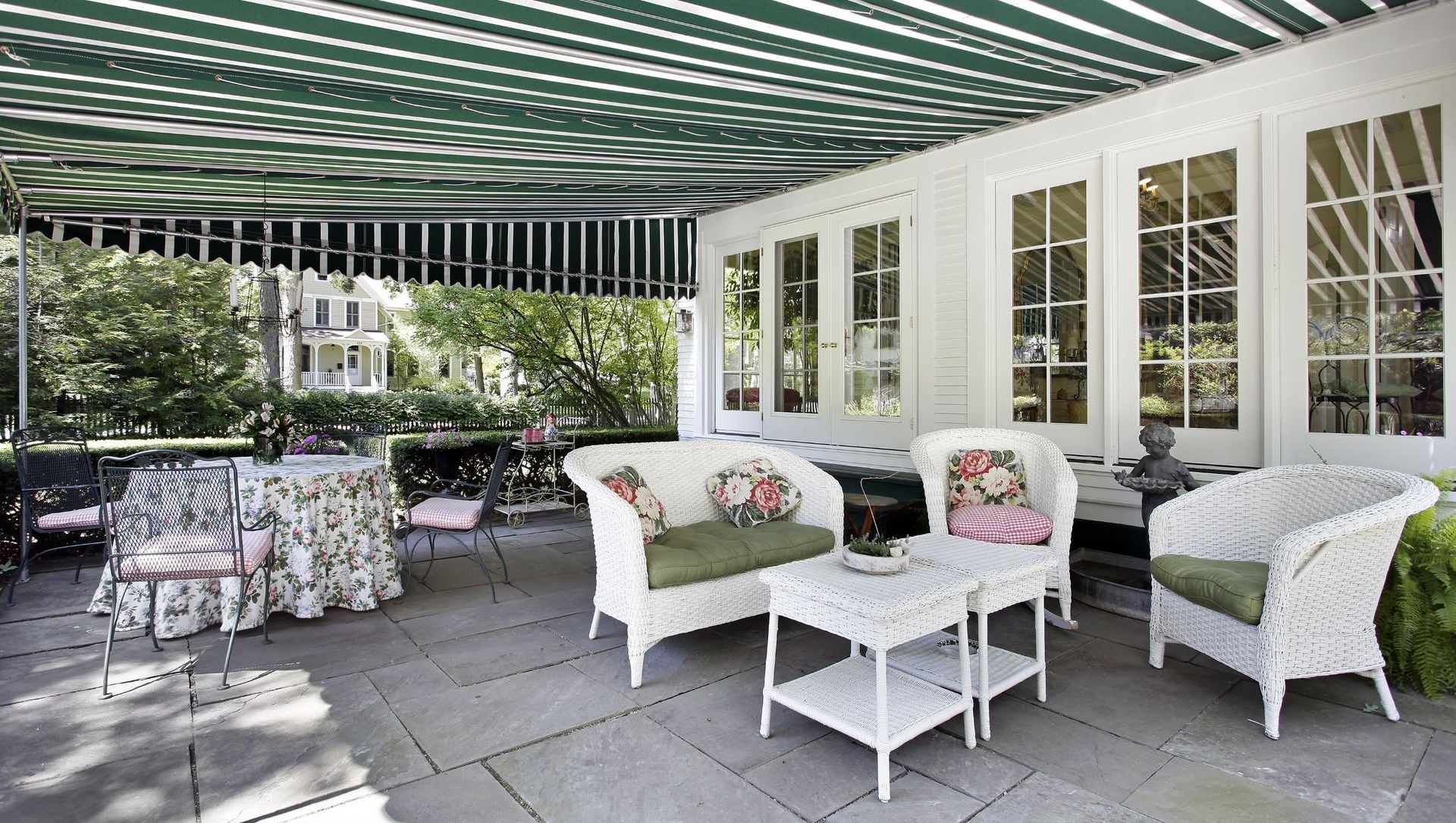 A patio with white furniture and a green and white striped awning.