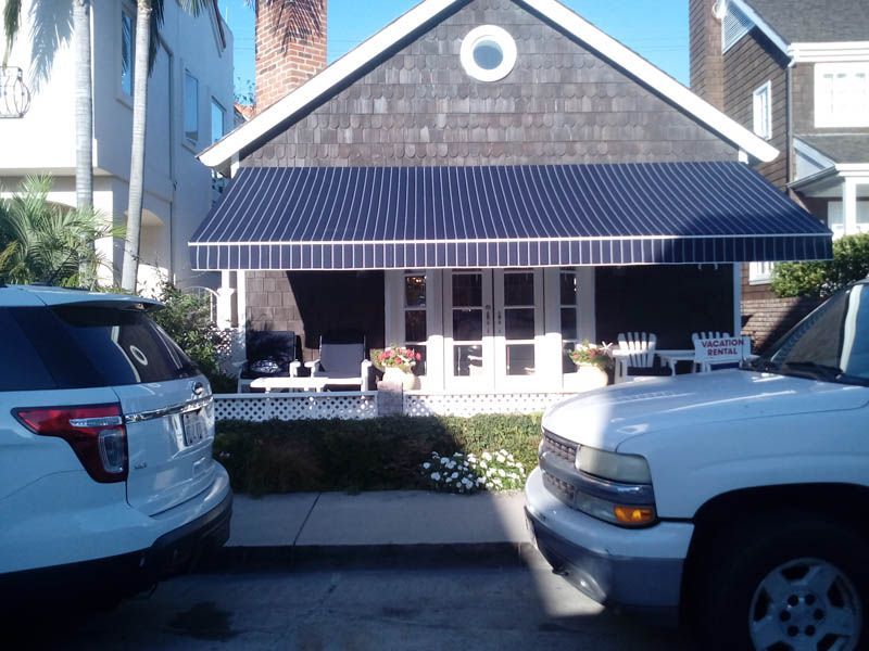 A white suv is parked in front of a house with a blue awning