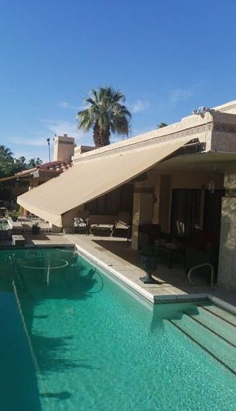 A house with a swimming pool and an awning over it.