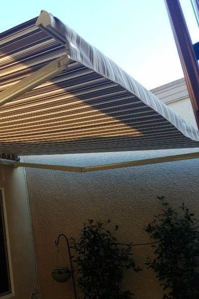 A large awning is sitting on top of a patio next to a building.