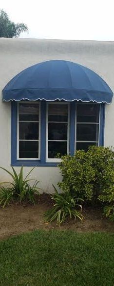 A white house with a blue awning over a window.