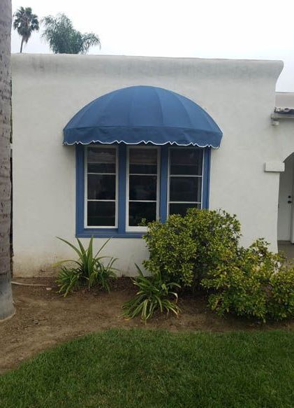 A white house with a blue awning over a window