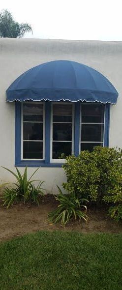 A white house with a blue awning over a window.