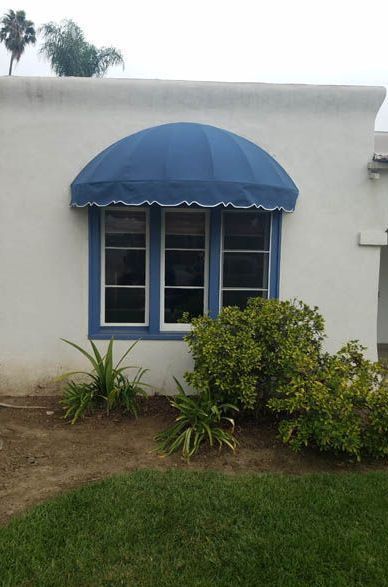 A white house with a blue awning over a window.