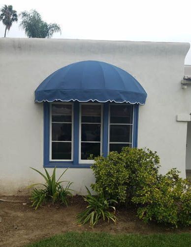 A white house with a blue awning over a window.