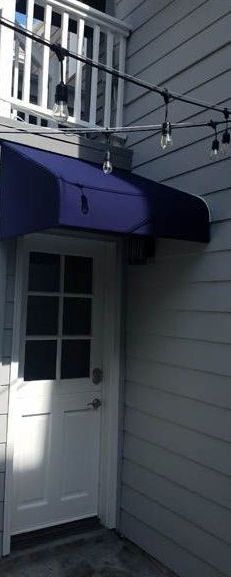 A house with a blue awning and a sliding glass door.