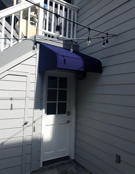 A white door with a blue awning over it