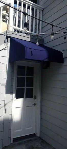 A white door with a blue awning over it.