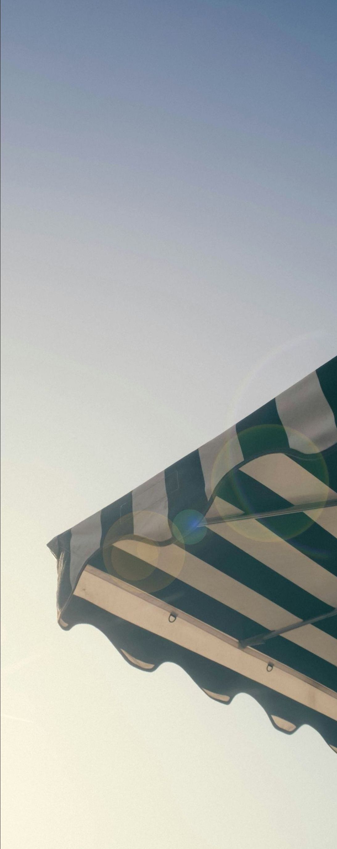 A black and white striped awning is against a blue sky.