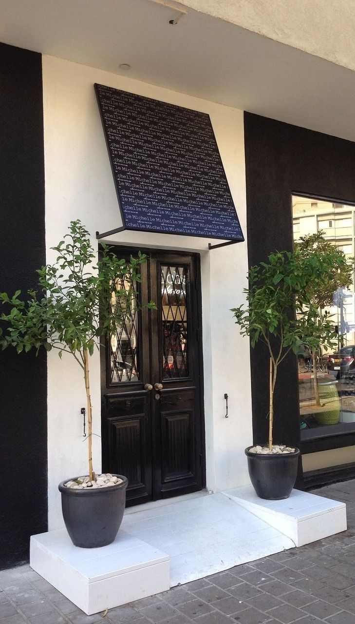 A black and white building with potted plants in front of it