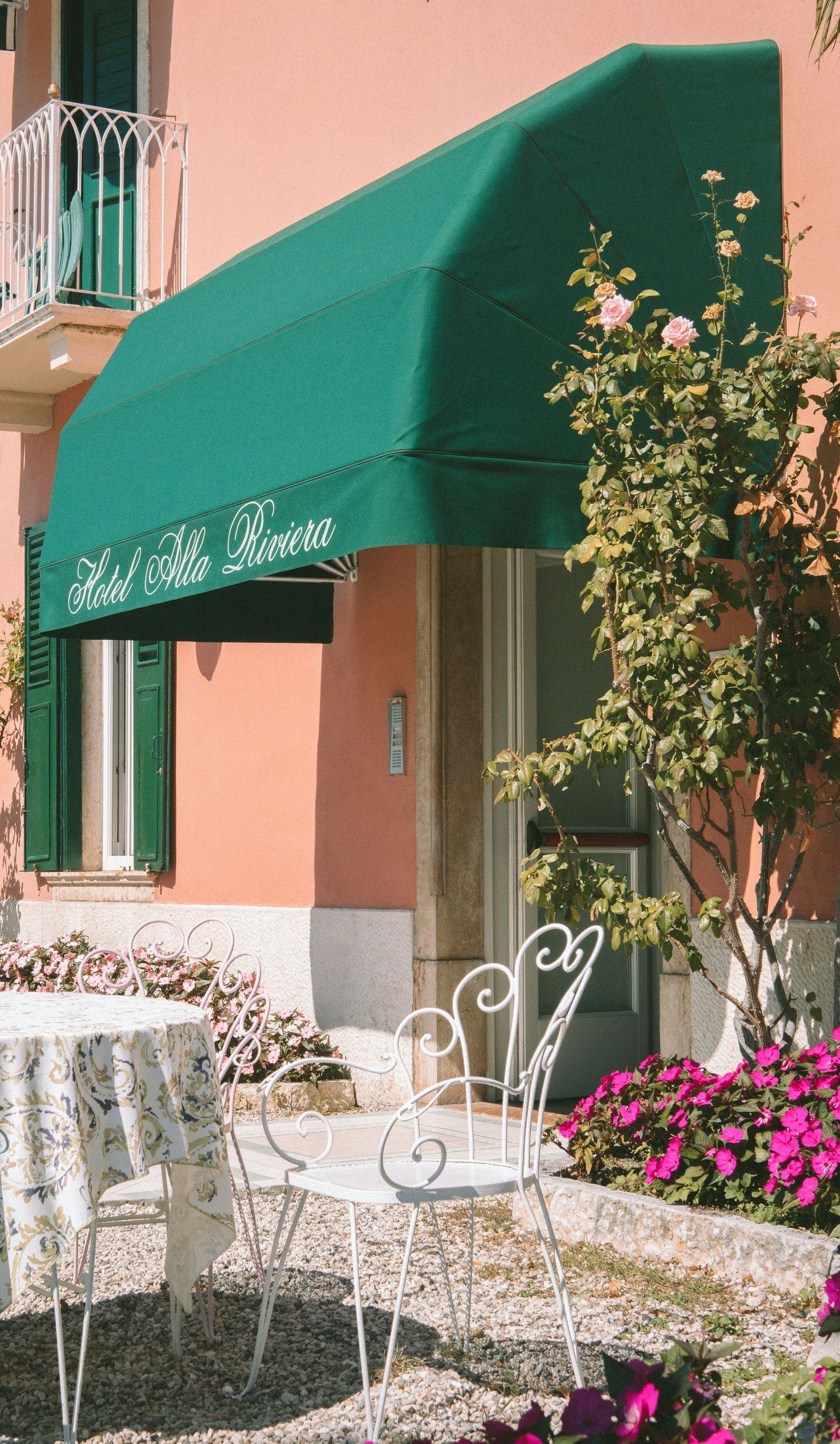A green awning over a table and chairs in front of a pink building