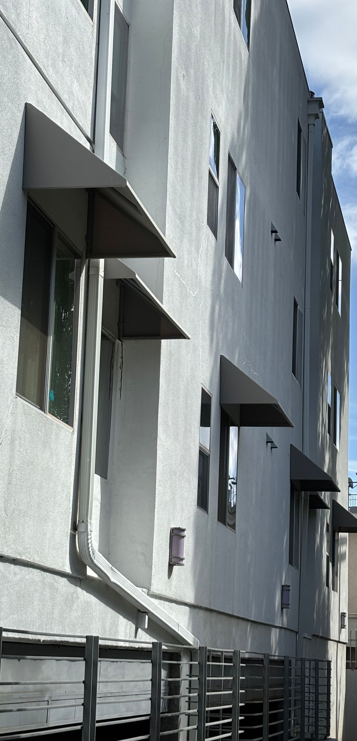 Gray building with awnings, windows, and a metal railing.