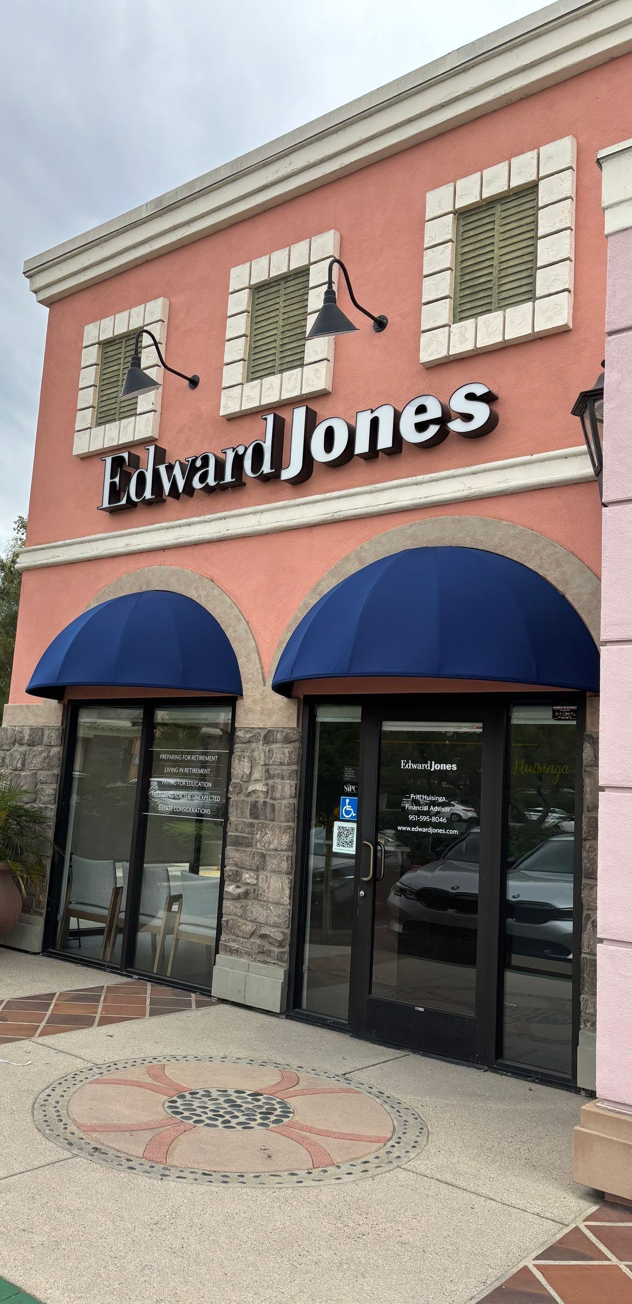 Exterior of an Edward Jones financial advisor office with a pink facade and blue awnings.