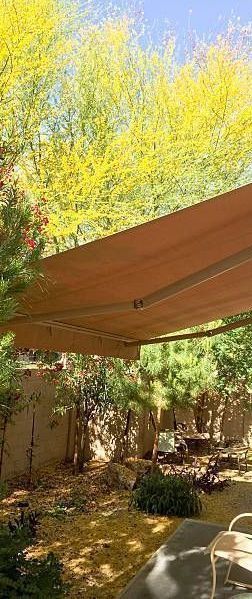 A large awning is covering a patio in a backyard.