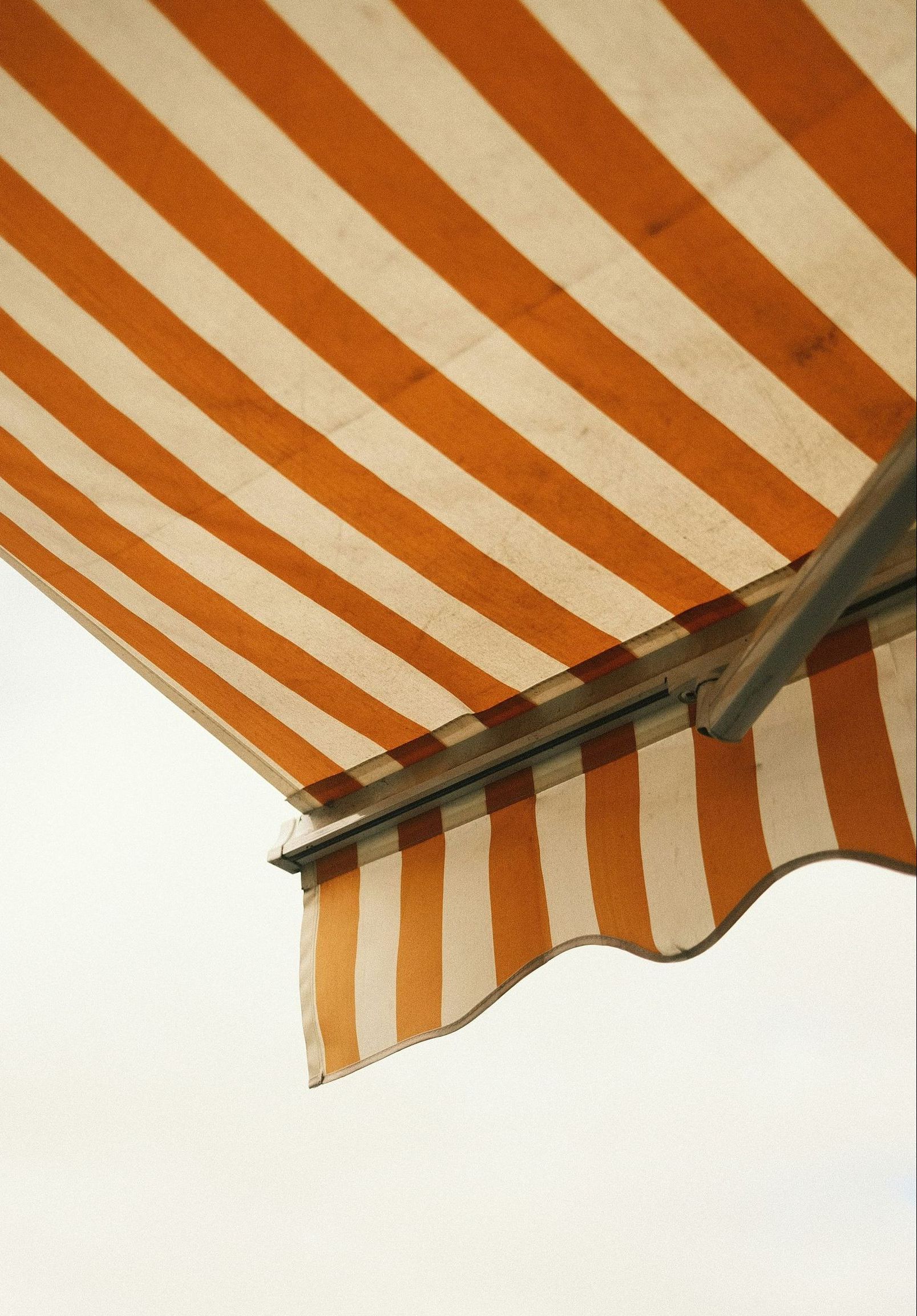 An orange and white striped awning against a white sky