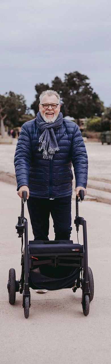 A man is walking with a walker on a dirt road.